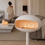 Poêle éthanol blanc mat allumé près d'un canapé, ambiance déco cosy et lumière douce